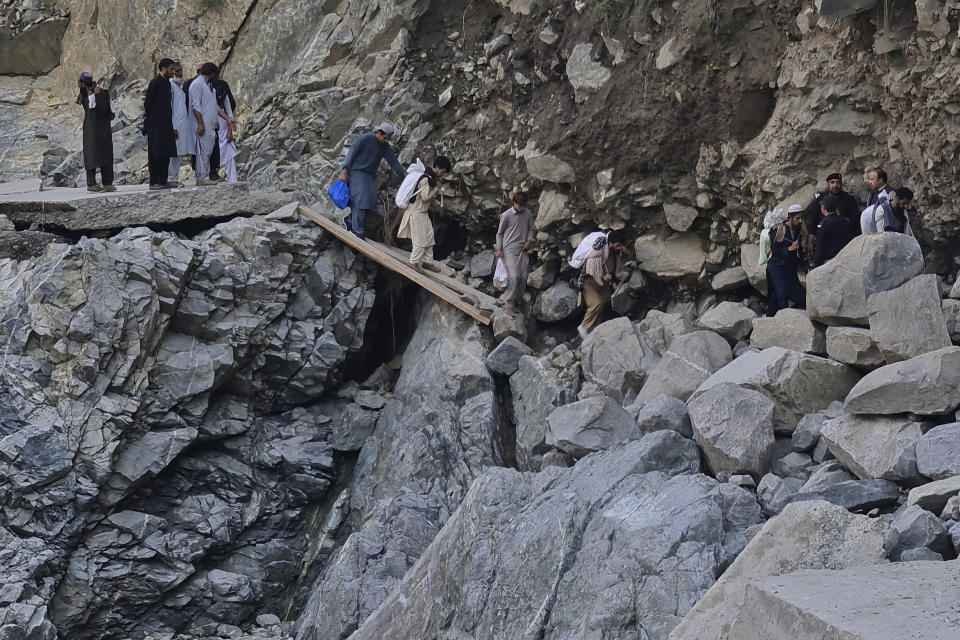 Local residents cross a portion of road destroyed by floodwaters in Kalam Valley in northern Pakistan, Tuesday, Aug. 30, 2022. Officials in Pakistan raised concerns Wednesday over the spread of waterborne diseases among thousands of flood victims as flood waters from powerful monsoon rains began to recede in many parts of the country. (AP Photo/Sherin Zada)