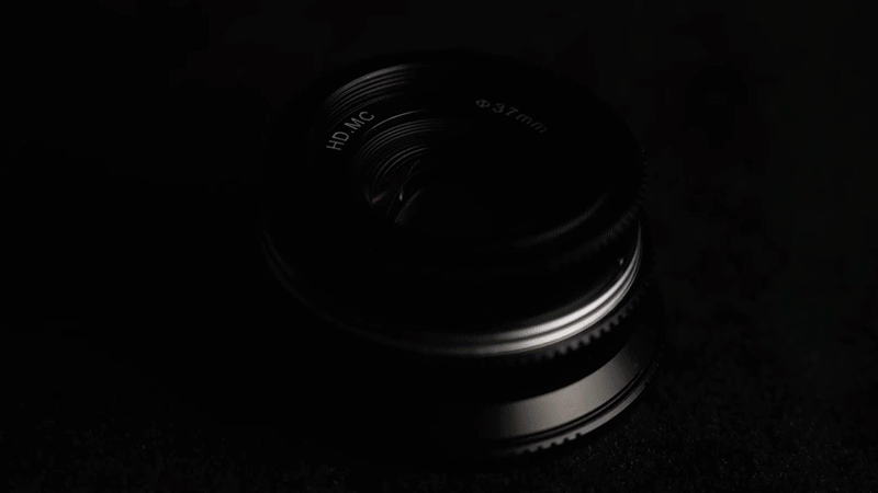  Pergear 25mm f/1.7 lens, in pitch blackness, with moving light highlighting the edges. 