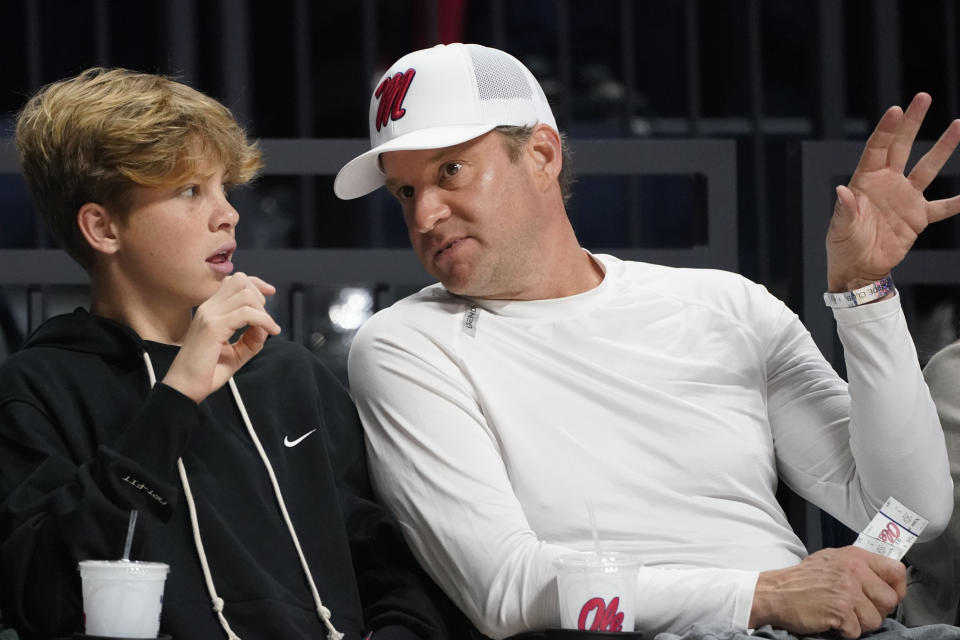 Mississippi head football coach Lane Kiffin, right, talks with his son Knox during the second half of an NCAA college basketball game against Bryant, Sunday, Dec. 31, 2023, in Oxford, Miss. (AP Photo/Rogelio V. Solis)