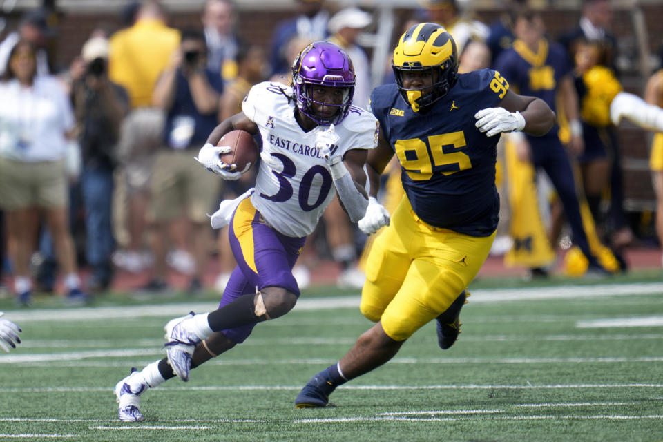 East Carolina running back Javious Bond (30) runs from Michigan defensive lineman Trey Pierce (95) in the second half of an NCAA college football game in Ann Arbor, Mich., Saturday, Sept. 2, 2023. (AP Photo/Paul Sancya)