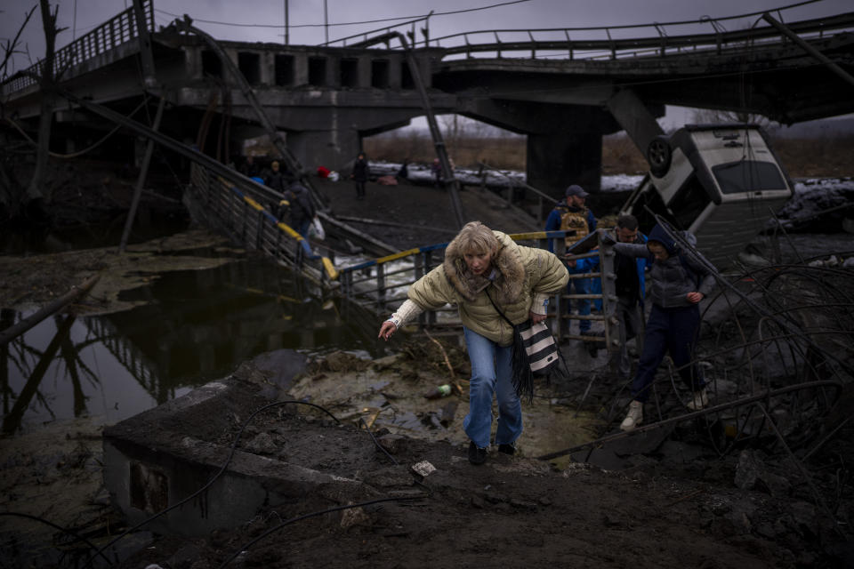 A woman runs as she flees with her family across a destroyed bridge in the outskirts of Kyiv, Ukraine, Wednesday, March 2. 2022. Russia renewed its assault Wednesday on Ukraine’s second-largest city in a pounding that lit up the skyline with balls of fire over populated areas, even as both sides said they were ready to resume talks aimed at stopping the new devastating war in Europe. (AP Photo/Emilio Morenatti)