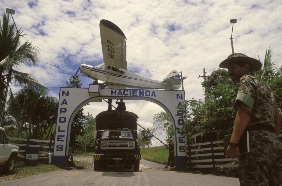 The gates to Hacienda Nápoles, Pablo Escobar's private estate in Columbia, with a man with a gun standing to the side.