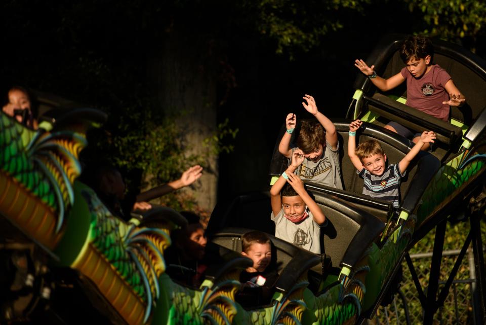 Kids throw their hands in the air as they ride a rollercoaster on the opening day of the Cumberland County Fair on Friday, Sept. 3, 2021.