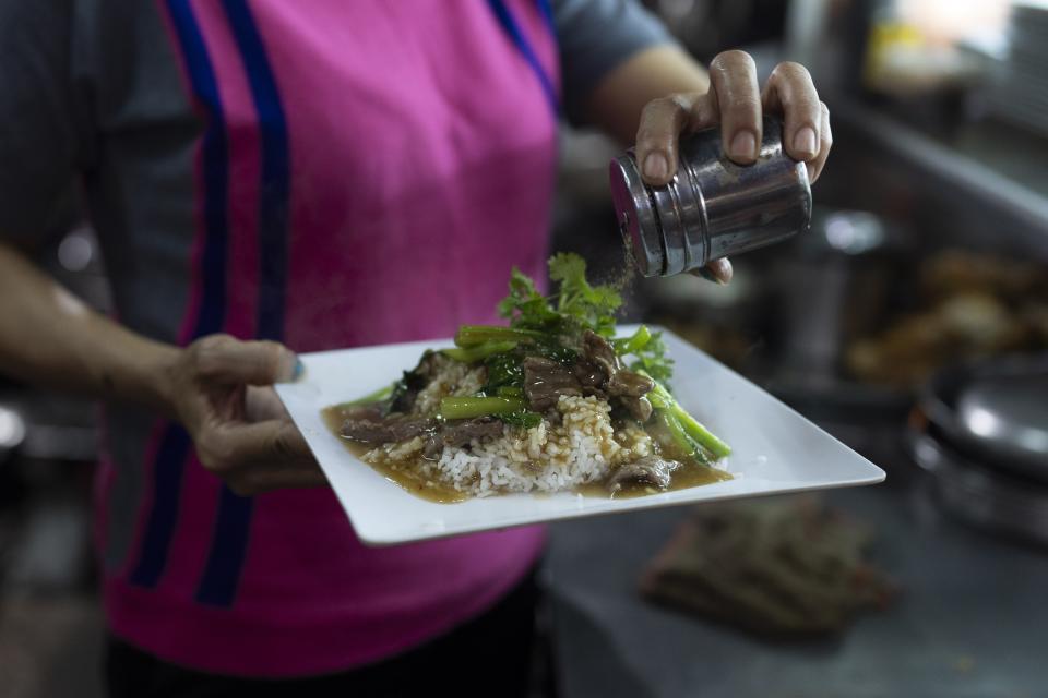 A restaurant worker sprinkles crushed pepper over a rice dish in Ho Chi Minh City, Vietnam, Wednesday, Jan. 24, 2024. Rice isn't just the mainstay of most meals, it is considered a gift from the gods and continues to be venerated. (AP Photo/Jae C. Hong)