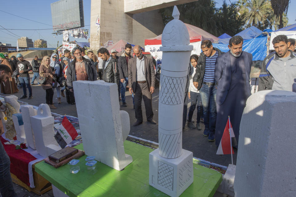 In this Friday, Dec. 20, 2019, photo, protesters attend the opening of an art exhibition in Tahrir square, Baghdad, Iraq. Tahrir Square has emerged as a focus of the protests, with protesters camped out in dozens of tents. Dozens of people took part in the simple opening of the sculpture exhibition. (AP Photo/Nasser Nasser)
