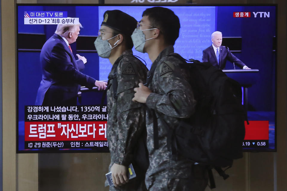 FILE - In this Oct. 23, 2020, file photo South Korean army soldiers pass by a TV screen showing a live broadcast of U.S. President Donald Trump, left, and Democratic presidential candidate former Vice President Joe Biden during the final presidential debate, at the Seoul Railway Station in Seoul, South Korea. The Korean letters read "U.S. presidential election TV debate." (AP Photo/Ahn Young-joon, File)