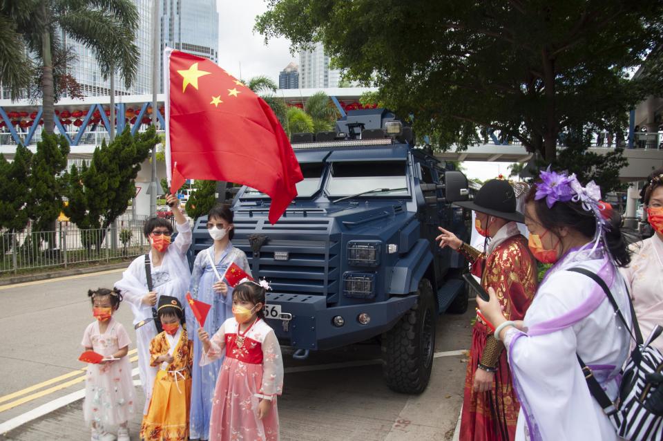 Patriots wave Chinese flags in front of an armored police vehicle during the celebrations on Friday.  (Mithil Aggarwal / NBC News)