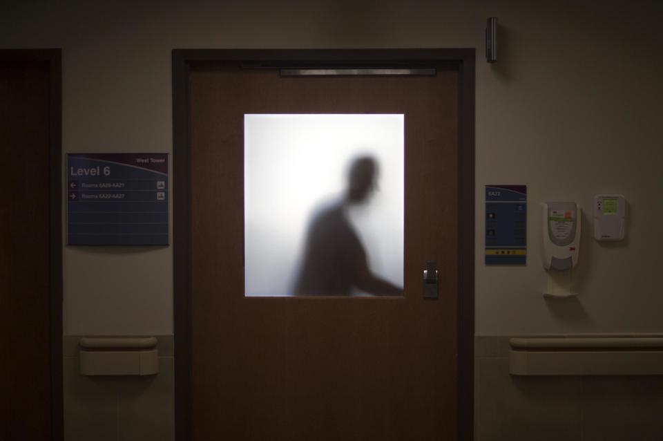 In this Friday, Jan. 24, 2014 photo, a doctor is silhouetted against a glass window while opening a door to leave an exam room after visiting a patient at Grady Memorial Hospital, in Atlanta. In two years, federal payments to hospitals treating a large share of the nation’s poor will begin to evaporate under the premise that more people than ever will have some form of insurance under the federal health care law. The problem is that many states have refused to expand Medicaid, leaving public safety net hospitals there in a potentially precarious financial situation and elected officials facing growing pressure to find a fiscal fix. And in an election year, Democrats are using the decision by Republican governors not to expand Medicaid as a major campaign issue and arguing the hospital situation could have been avoided. (AP Photo/David Goldman)