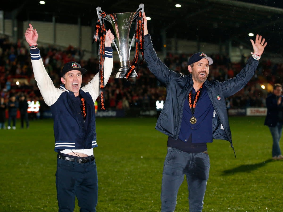 Wrexham co-owners Rob McElhenney and Ryan Reynolds celebrate with the trophy on the pitch after Wrexham win the National League and promotion to League (Action Images/Reuters)