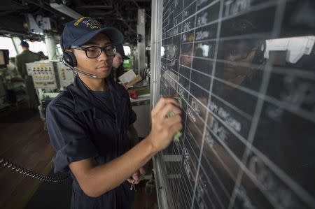 Seaman Kyren Mounsombath updates navigational information on the bridge of the amphibious assault ship USS Bonhomme Richard (LHD 6), flagship of the Bonhomme Richard Expeditionary Strike Group, in the South China Sea. David Holmes/U.S. Navy/Handout via REUTERS