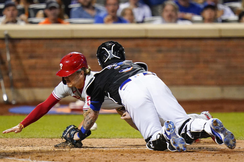 Philadelphia Phillies' Bryson Stott, left, slides past New York Mets catcher Tomas Nido to score on a sacrifice fly by Alec Bohm during the 10th inning of a baseball game Friday, Aug. 12, 2022, in New York. (AP Photo/Frank Franklin II)