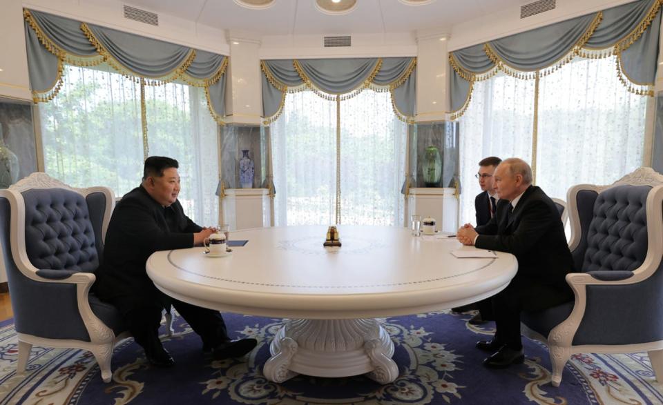 Kim Jong Un and Vladimir Putin sit at a table for one-on-one talks.