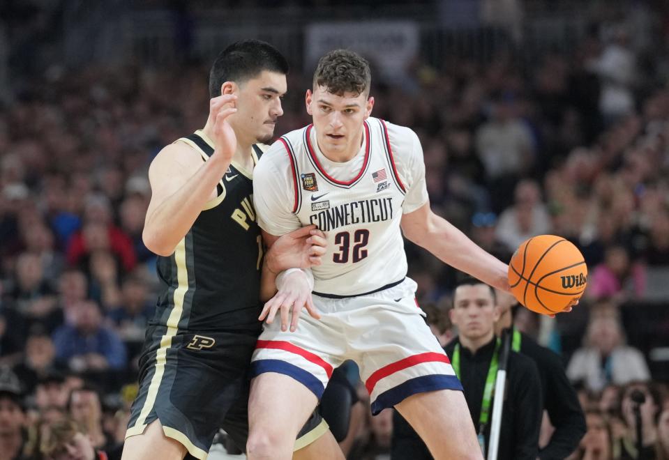 Apr 8, 2024; Glendale, AZ, USA; Connecticut Huskies center Donovan Clingan (32) dribbles against Purdue Boilermakers center Zach Edey (15) in the national championship game of the Final Four of the 2024 NCAA Tournament at State Farm Stadium. Mandatory Credit: Robert Deutsch-USA TODAY Sports