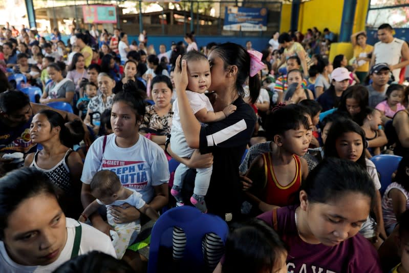 FILE PHOTO: Mothers hold their children while waiting in line to receive free polio vaccine during a government-led mass vaccination program in Quezon City