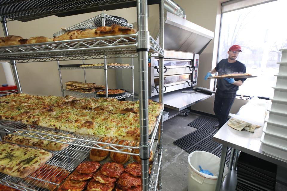 Billy Gushue pulls a steaming hot pizza from the oven as he works to fill the racks with pizzas for that day as the lunch hour approaches.