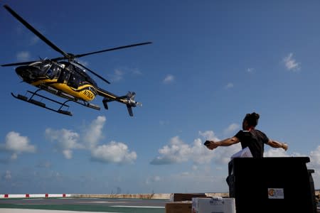 A volunteer of the NGO World Central Kitchen gestures as a helicopter leaves after delivering food for distribution, after Hurricane Dorian hit the Abaco Islands in Marsh Harbour