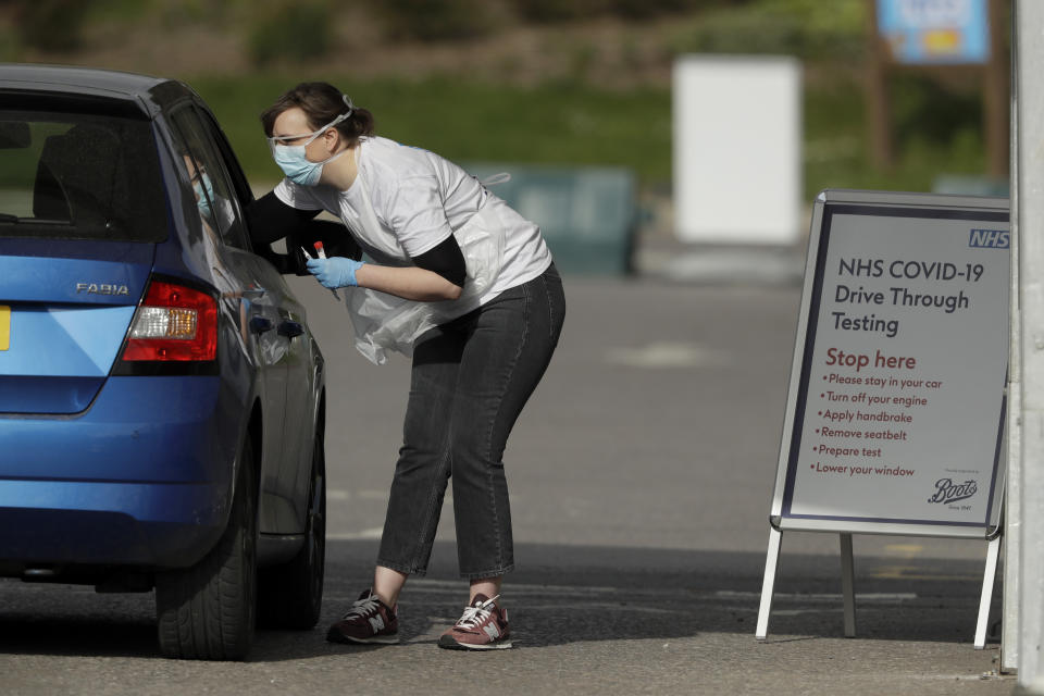 A NHS (National Health Service) worker is tested for Covid-19 at a drive-through testing centre in a car park at Chessington World of Adventures, Greater London, Saturday, April 4, 2020. The new coronavirus causes mild or moderate symptoms for most people, but for some, especially older adults and people with existing health problems, it can cause more severe illness or death. (AP Photo/Matt Dunham)