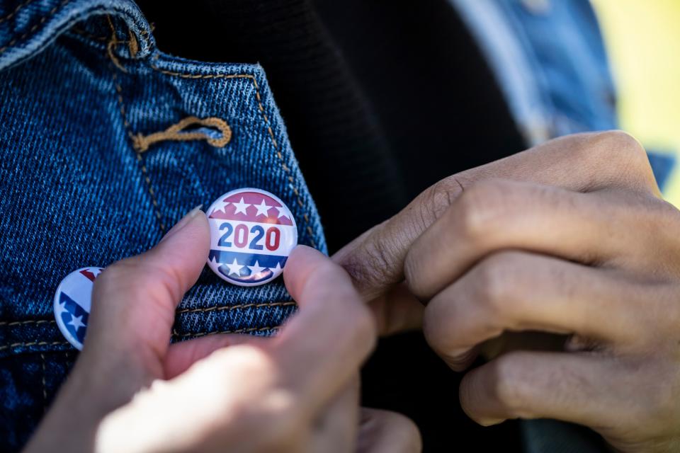 A young African American woman holding a voting badge. (LPETTET via Getty Images)