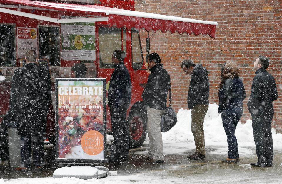 People wait in line at a food truck in Boston as snow from the latest storm to hit the area begins to fall, Tuesday, Feb. 18, 2014. (AP Photo/Michael Dwyer)