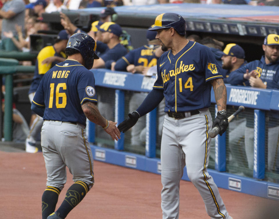 Milwaukee Brewers' Jace Peterson (14) congratulates Kolten Wong for scoring on a triple by Christian Yelich during the first inning of a baseball game against the Cleveland Indians in Cleveland, Saturday, Sept. 11, 2021. (AP Photo/Phil Long)