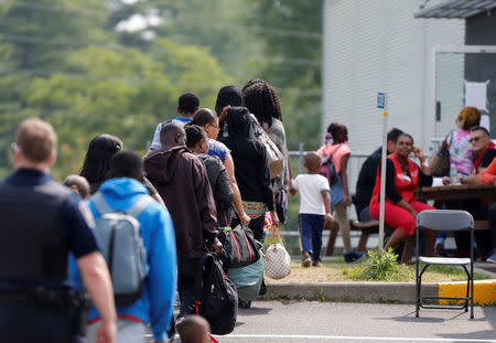 FILE PHOTO: A group of asylum seekers wait to be processed after being escorted from their tent encampment to the Canada Border Services in Lacolle, Quebec, Canada, August 11, 2017. REUTERS/Christinne Muschi/File Photo