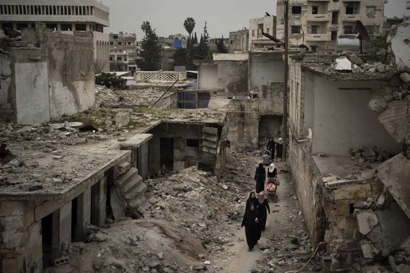 敘利亞伊德利卜省（Idlib），居民走在空襲殘垣間。（美聯社）