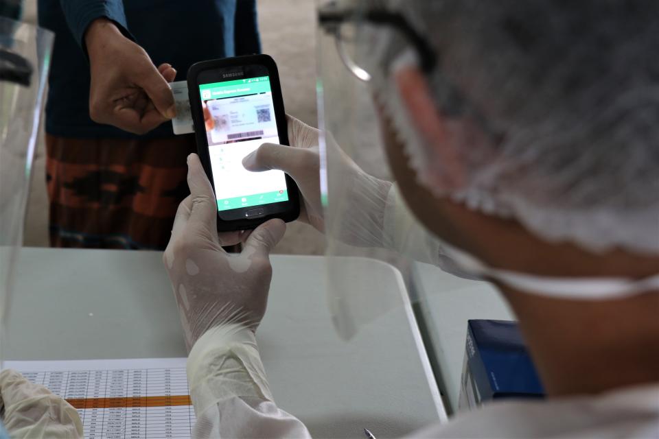 A swab administrator making use of the Mobile Express Scanner application to scan a migrant worker's Work Pass. (PHOTO: Mindef)