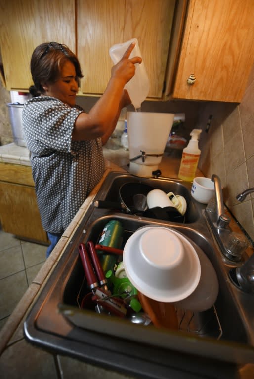Maria Jimenez demonstrates how they use bottled water to wash dishes in the drought affected town of Monson, California on June 23, 2015