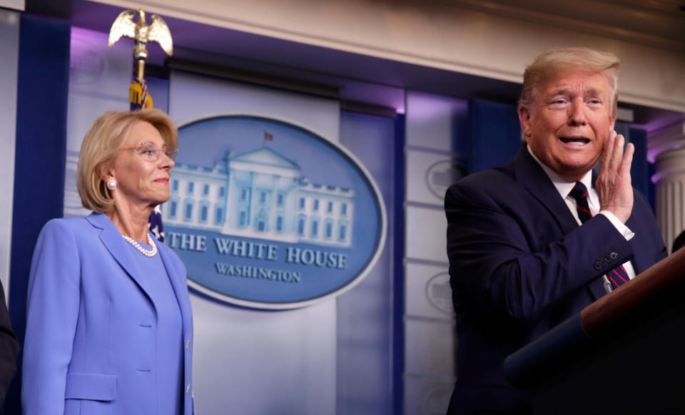 U.S. President Donald Trump addresses the daily coronavirus response briefing as Education Secretary Betsy DeVos looks on at the White House in Washington, U.S., March 27, 2020. REUTERS/Jonathan Ernst