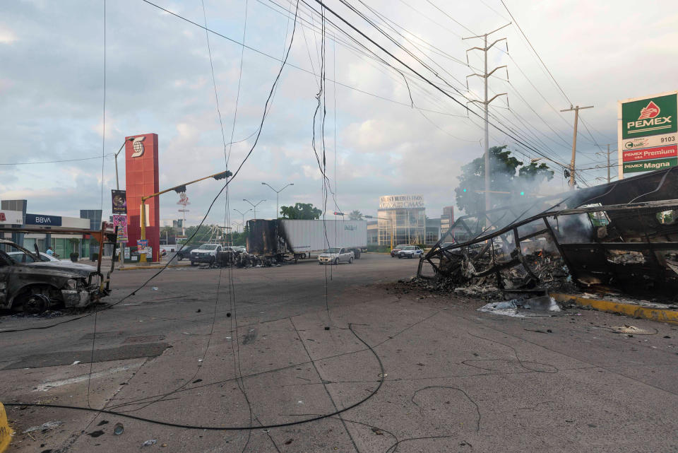 Burnt vehicles used by gunmen smolder on an intersection, one day after street battles with security forces, in Culiacan on Oct. 18. | Augusto Zurita—AP
