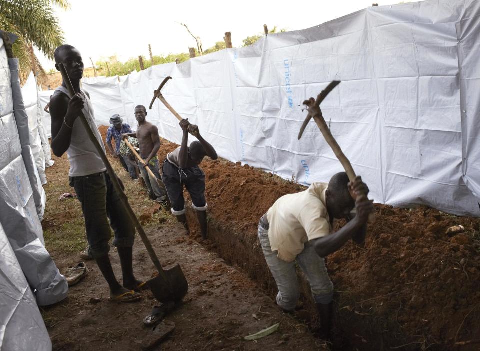 People dig a trench to be use as latrines for displaced residents camping at the Catholic church in Bangui, Central African Republic, December 10, 2013. France's president flew into Central African Republic hours after two French soldiers were killed in fighting and praised his troops for tackling "horrendous violence" against women and children and helping avert a slide into civil war. Pictures taken December 10, 2013. REUTERS/Sam Phelps (CENTRAL AFRICAN REPUBLIC - Tags: CIVIL UNREST MILITARY POLITICS RELIGION CONFLICT)