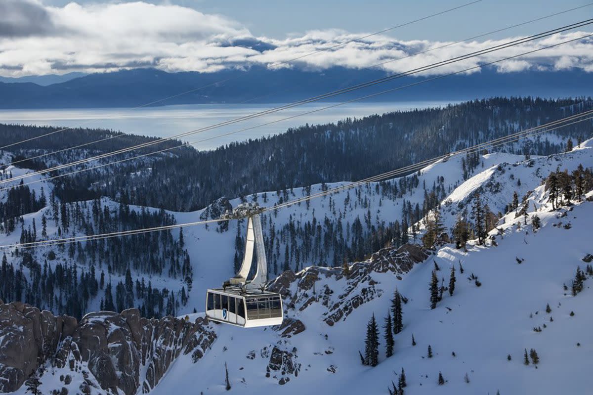 Ski lift hanging in Squaw Valley Resort, North Lake Tahoe, California, high in the snow-covered mountains with Lake Tahoe in the background, blue-ish light on the snow