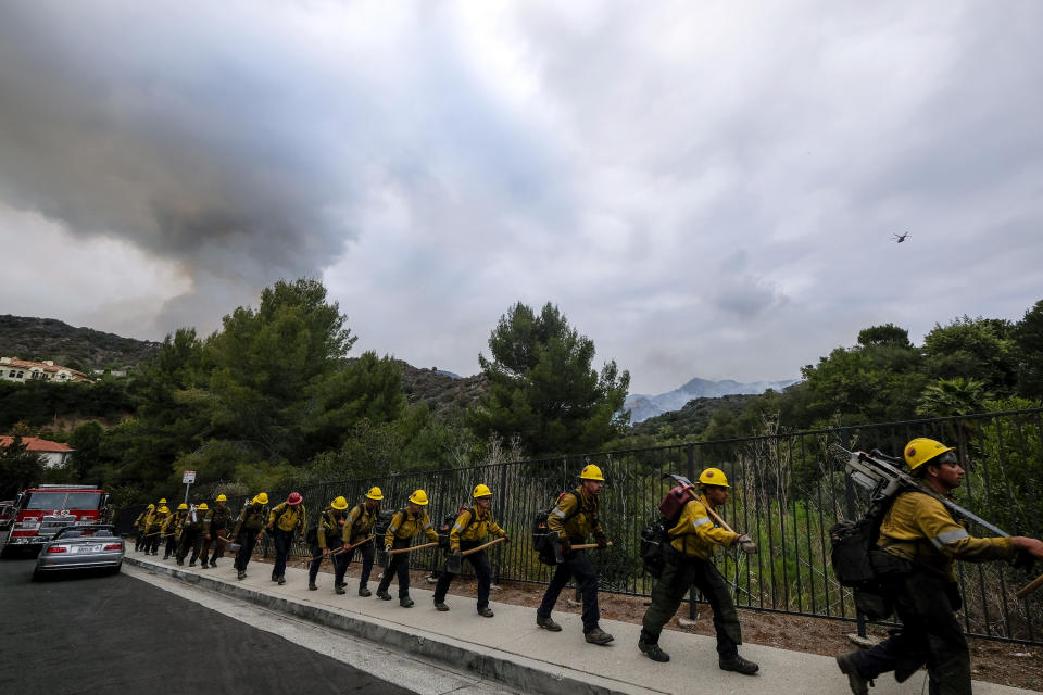 Members of the Hotshots fire crew walk in line during a wildfire in the Pacific Palisades area of Los Angeles, Sunday, May 16, 2021. (AP Photo/Ringo H.W. Chiu)