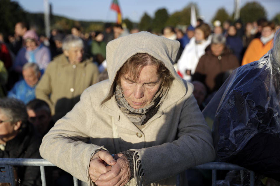 A woman prays as she waits for the arrival of Pope Francis to celebrate mass, at the Santakos Park, in Kaunas, Lithuania, Sunday, Sept. 23, 2018. (AP Photo/Andrew Medichini)