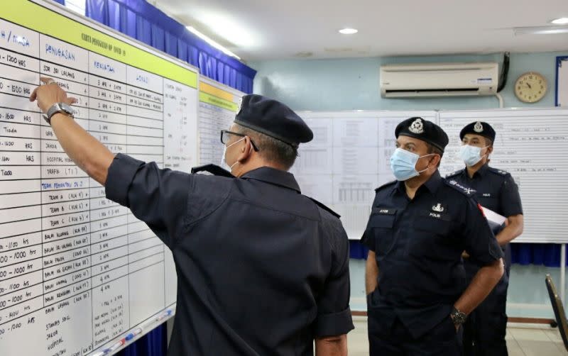 Datuk Ayob Khan Mydin Pitchay (second from left) being briefed on the enhanced movement control order on the two villages in Simpang Renggam during his visit today. — Picture courtesy of the Johor Police