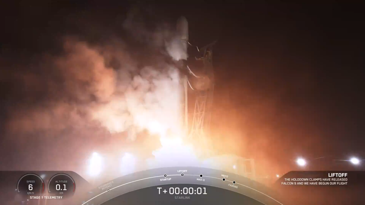  A white SpaceX rocket launches at night from launch pad. 