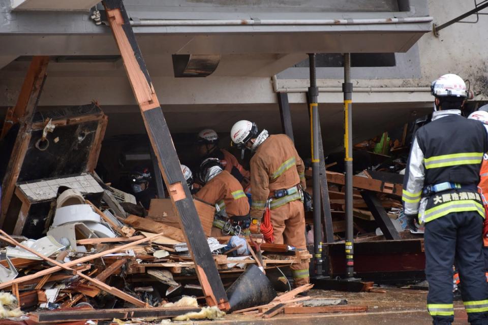 Firefighters work at the scene where a building toppled over and crushed a house in the city of Wajima (JIJI Press/AFP via Getty)