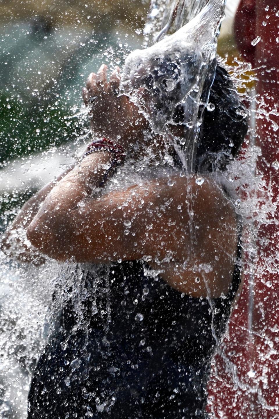 A woman cools off at a fountain during hot weather at the River Trails Park District Woodland Trails Pool in Mount Prospect, Ill., Thursday, July 21, 2022.