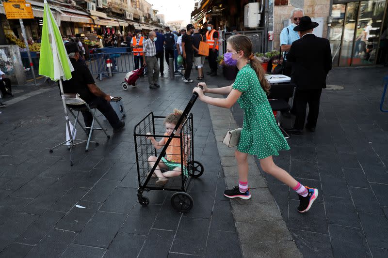 A girl pushes a trolley with a toddler in it in a main market ahead of Yom Kippur, the Jewish Day of Atonement as Israel is set to tighten its second nationwide coronavirus disease (COVID-19) lockdown amid a rise in infections, later today, in Jerusalem