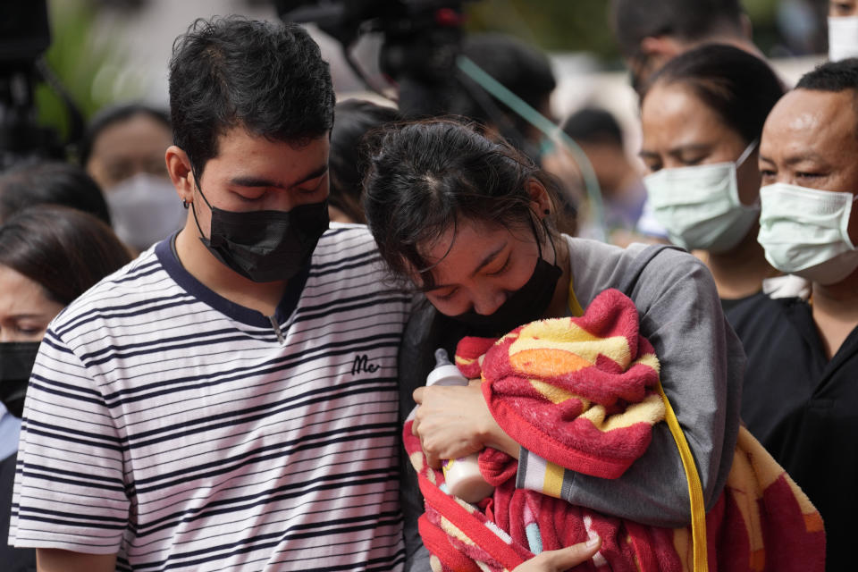 La familia de una de las víctimas del asalto una guardería llora agarrada a su manta y biberón durante un acto para recordar a los fallecidos en el ataque, en Uthai Sawan, en el noreste de Tailandia, el 7 de octubre de 2022. (AP Foto/Sakchai Lalit)