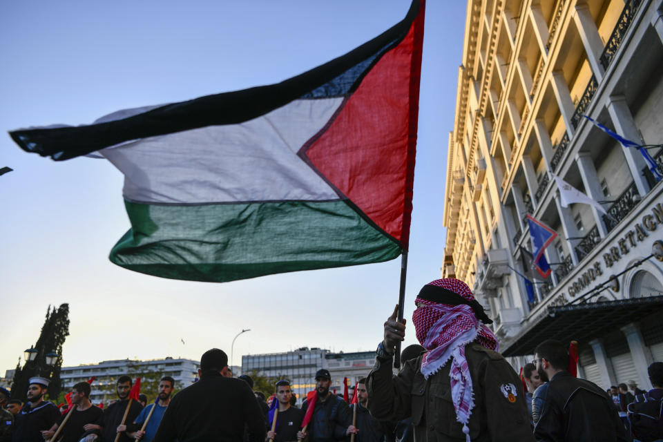 A pro-Palestinian protester holds a Palestinian flag during a rally in Athens, Friday, Nov. 17, 2023. Thousands of people are marching through central Athens to mark the 50th anniversary of a pro-democracy student uprising that was violently put down by the military dictatorship ruling Greece in 1973. (AP Photo/Michael Varaklas)