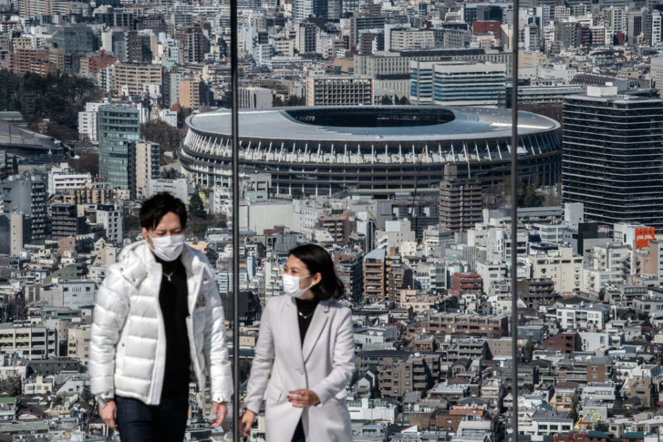 A couple wearing face masks walks away after viewing the New National Stadium, the main stadium for the Tokyo 2020 Olympics, as they visit the Shibuya Sky observation deck on March 24, 2020 in Tokyo, Japan.<span class="copyright">Carl Court/Getty Images</span>