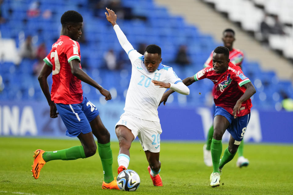 Félix García, de Honduras, disputa la pelota con Adama Bojang, a la izquierda, de Gambia durante el debut de ambas selecciones en el Grupo F del Mundial Sub20 de Argentina en el estadio Malvinas Argentinas de Mendoza, Argentina, lunes 22 de mayo, 2023. (AP Foto/Natacha Pisarenko)