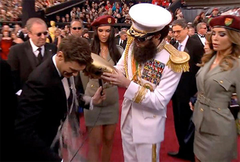 <p>Done up to the nines in his full military regalia as dictator Admiral General Aladeen, Sacha Baron Cohen approached a wary Ryan Seacrest on the Oscar red carpet, the most hallowed carpet in the world, carrying a suspicious-looking urn. In it was the “ashes of his tennis doubles partner” Kim Jong-il, the late leader of North Korea. Mr. Seacrest slapped on a fake smile when it was emptied on him, but you could tell he wasn’t best pleased at having his tuxedo ruined. <i>(Credit: E!)</i></p>
