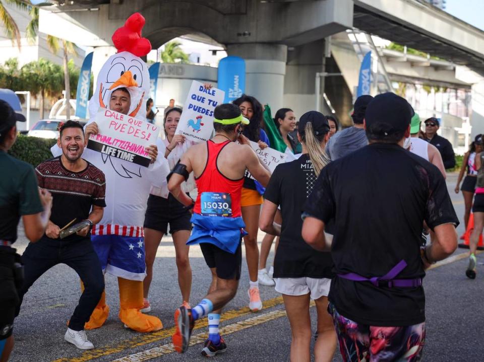 Spectators Becker Rosales, 31, left, David Vargas, 30, in the chicken outfit, Leti Romano, 31, center, cheer on runners after crossing the Venetian Causeway while they participated in the Life Time Miami Marathon and Half Marathon on Sunday, Jan. 29, 2023, in Miami, Fla.