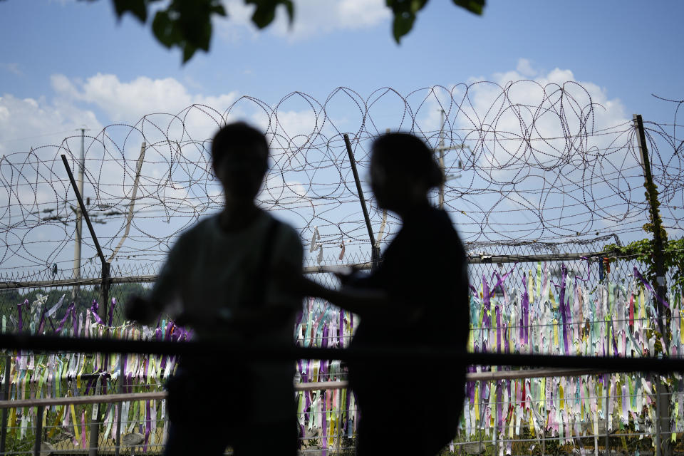 Visitors walk near a wire fence decorated with ribbons written with messages wishing for the reunification of the two Koreas at the Imjingak Pavilion in Paju, South Korea, Wednesday, June 26, 2024. A suspected hypersonic missile launched by North Korea exploded in flight on Wednesday, South Korea's military said, a development that comes as North Korea is protesting the regional deployment of a U.S. aircraft carrier for a trilateral military drill with South Korea and Japan. (AP Photo/Lee Jin-man)