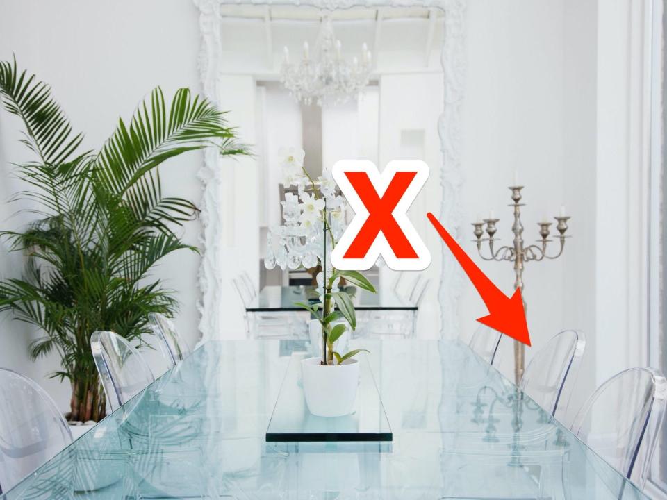 A room with a glass table and clear chairs with an x and arrow pointing at one of the chairs.