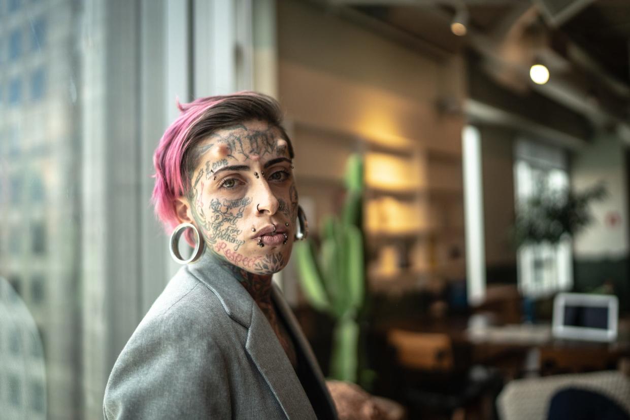 Eine Frau im Geschäftsanzug mit Gesichtstattoos. (Symbolbild) - Copyright: FG Trade/Getty Images