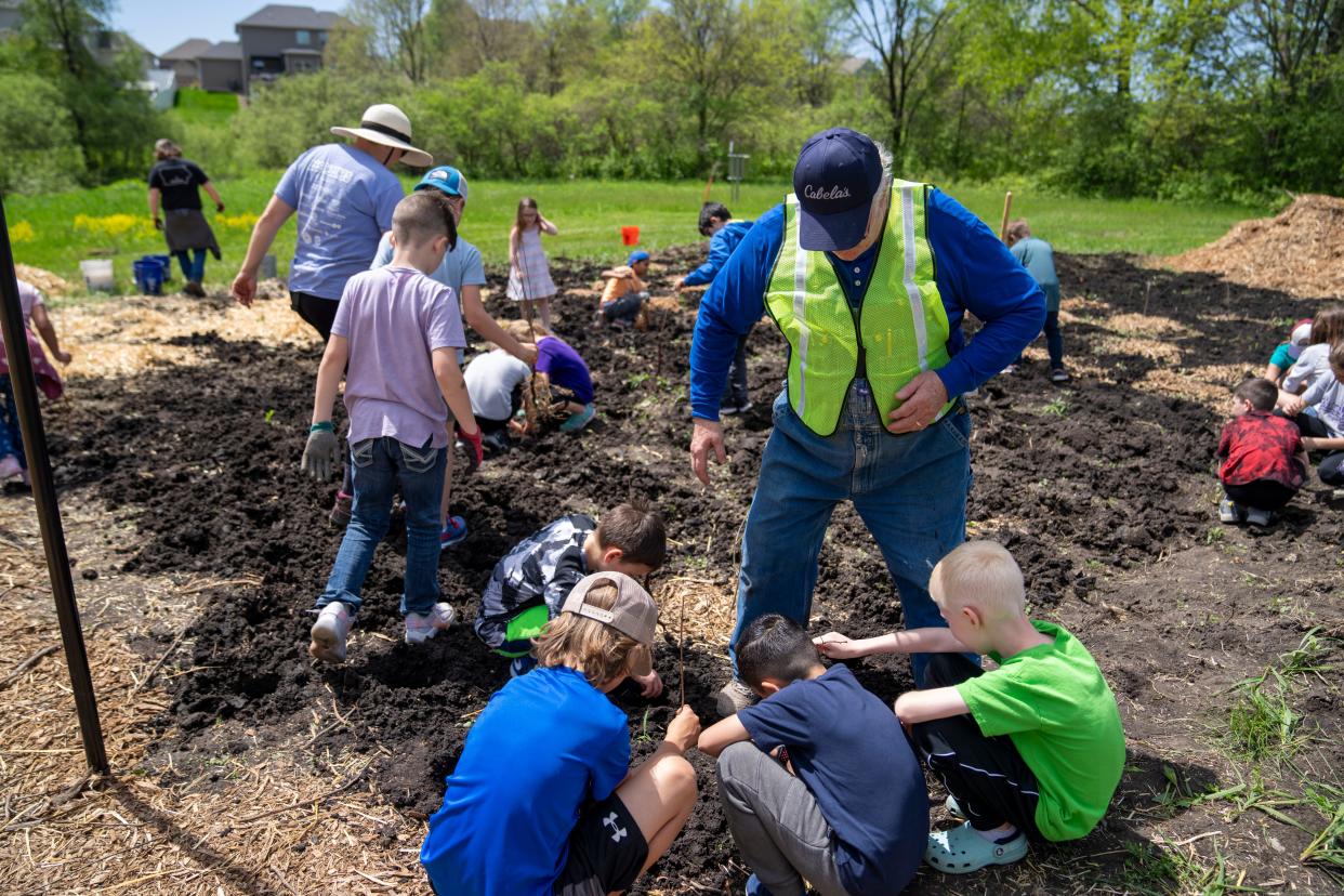 Students from Brookview Elementary School plant trees and shrubs to a create a mini-forest at Brookview Park in West Des Moines, Friday, May 3, 2024.