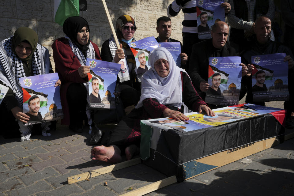 Palestinians react while sitting around a mock coffin as they hold a symbolic funeral of a prisoner Nasser Abu Hamid during a protest in front of the International Committee of the Red Cross office, Tuesday, Dec. 20, 2022, in Gaza City, after he died of lung cancer in Israel. Abu Hamid was a former leader of the Al Aqsa Martyrs' Brigade, the armed wing of Palestinian President Mahmoud Abbas's Fatah party. He had been serving seven life sentences after being convicted in 2002 for involvement in the deaths of seven Israelis during the second Palestinian intifada, or uprising, against Israel's occupation in the early 2000s. (AP Photo/Adel Hana)